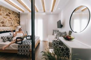 une femme assise sur un lit dans une pièce avec miroir dans l'établissement Rodillo Apartments, à Plaka