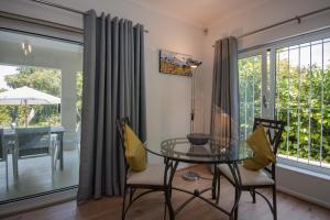 a dining room with a glass table and chairs at Garden- Pool flat with Solar Electricity in Somerset West +14 photos
