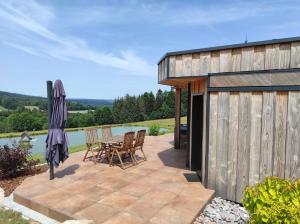 eine Terrasse mit einem Tisch und Stühlen neben einem Gebäude in der Unterkunft Nature Cottage Vosges Spa Le Cerf in Anould