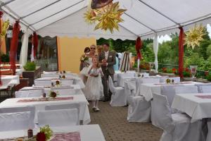 eine Braut und ein Bräutigam, die den Gang eines Festes mit weißen Tischen entlang gehen in der Unterkunft Gasthof Alter Felsenkeller in Naumburg