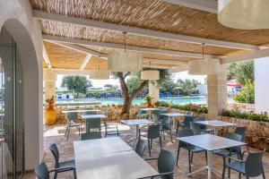 un ristorante con tavoli e sedie e una piscina di PORTO CESAREO CAMPING & Village a Porto Cesareo