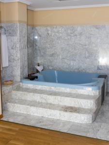 baño con bañera azul y pared de piedra en Hotel Puerta de Monfrague, en Malpartida de Plasencia