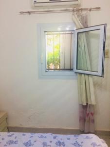 a window in a room with a bed and a mirror at Small apartment with Garden in Cairo