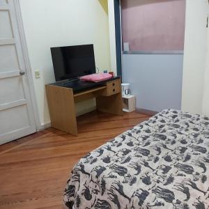 1 dormitorio con 1 cama y escritorio con TV en Cerca de todo Habitaciones en Buenos Aires