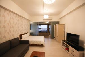a living room with a bed and a couch and a television at 晨曦溫泉宅 in Toucheng
