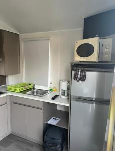 a small kitchen with a refrigerator and a microwave at Auberge des Etangs in Roussent