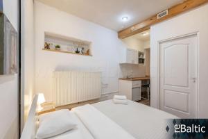 a white bedroom with a bed and a kitchen at St Anne studio in Vilnius