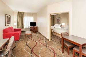 a hotel room with a bed and a red couch at Hawthorn Suites Bloomington in Bloomington