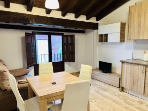 cocina y comedor con mesa de madera y sillas en Apartamentos Raíces en Mogarraz