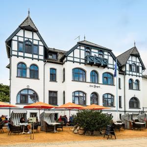 a large white building with tables and chairs in front of it at Hotel Asgard in Zinnowitz