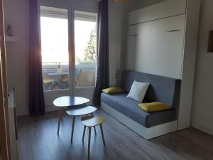 Una sala de estar con un sofá y una mesa y una ventana. en Studio Balcon Proche Hypercentre de Narbonne, en Narbona