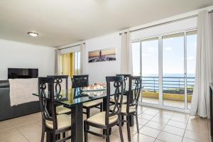 a dining room with a table and chairs with a view of the ocean at Bela Vista Sea View in Venda do Atalhinho