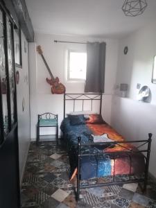 ein Schlafzimmer mit einem Bett in einem Zimmer mit einer Gitarre in der Unterkunft Les Amandiers de Jade in Saint-Agnet