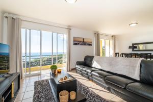 un soggiorno con divano in pelle nera e una grande finestra di Bela Vista Sea View a Venda do Atalhinho