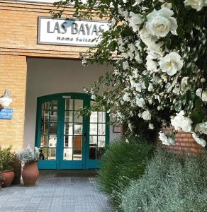 un bâtiment avec une porte bleue et des fleurs blanches dans l'établissement Las Bayas Home Suites, à Esquel