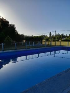 a pool of water with a fence and a field at Camping las islas in Panimávida