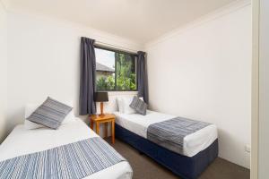 two beds in a room with a window at Hornsby Furnished Apartments in Hornsby