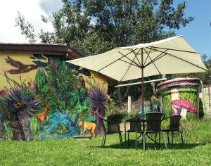 einen Tisch und Stühle unter einem Regenschirm im Gras in der Unterkunft casa campeche in Subachoque
