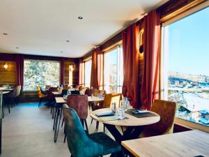 een restaurant met tafels en stoelen en grote ramen bij Hôtel Bel Angle in Les Angles