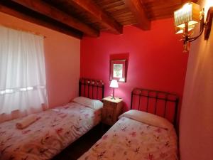 2 camas en una habitación con paredes rojas en Hotel Rural Casa Dera Hont, en Arrés