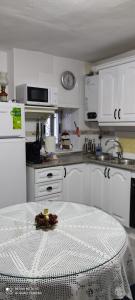 una cocina blanca con una mesa en el medio. en Casa Rural "La Casita", en Pujerra