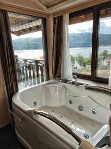 una gran bañera blanca en una habitación con ventana en OASIS RESORT RHODOPES en Dospat