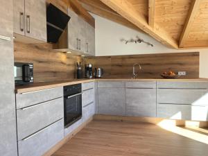 una cocina con electrodomésticos de acero inoxidable y techos de madera. en Sunnefleackle -Haus Lingenhöl, en Sonthofen