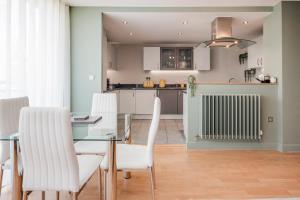 a kitchen and dining room with a glass table and white chairs at Perfect for visiting the Excel, O2, Canary Wharf - 15 mins from London City Airport in London