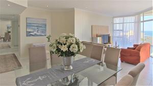 a living room with a glass table with a vase of flowers at Searock uMhlanga by WhereToGo in Durban