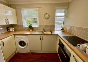 a kitchen with a sink and a washing machine at Cosy Bungalow Near Open Countryside in Felixstowe