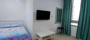 1 dormitorio con 1 cama y TV en la pared en 16 דירה מול הים ובריכה, en Bat Yam