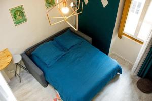 um quarto com uma cama com lençóis azuis e uma janela em Cosy à Guist'hau em Nantes