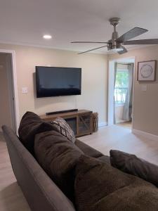 a living room with a couch and a flat screen tv at Cozy Home in a Golf kart neighborhood and private pool in Palm Harbor