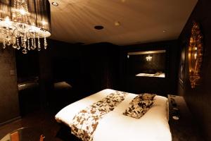 Un dormitorio con una cama con sábanas blancas y una lámpara de araña. en 旭川ホテルユニオン-大人専用 en Asahikawa