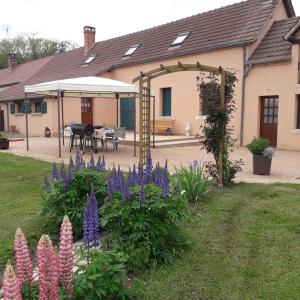 uma casa com um jardim com flores roxas no quintal em Gîte les petits loups em Thoury