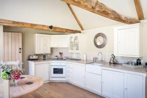a kitchen with white cabinets and a wooden table at Clematis cottage in Cheltenham