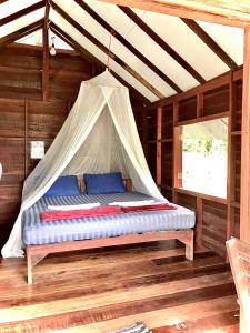 a bed in a wooden room with a tent at Frog Garden Hut in Ko Phayam