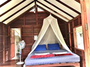 a bed in a room with a canopy at Frog Garden Hut in Ko Phayam