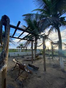 uma rede de descanso e uma cadeira numa praia com uma palmeira em Casa de Praia - Aracaju - Jatobá em Barra dos Coqueiros
