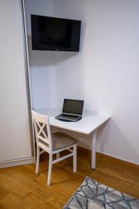 a laptop computer sitting on a white desk with a chair at Sky Apartments Novi Sad in Novi Sad