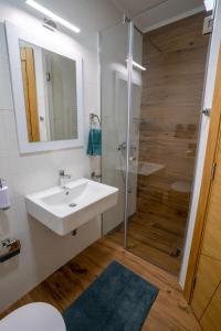 a white bathroom with a sink and a shower at Sky Apartments Novi Sad in Novi Sad