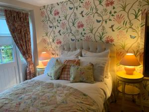 a bedroom with a bed with a floral wallpaper at Woodville Barn in Dunster