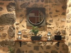 un mur en pierre avec un miroir et des lumières sur une étagère dans l'établissement Chez Marinou, à Chirols