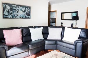 a black leather couch with three pillows on it at Casa do Sol in Ponta do Sol