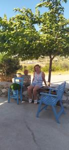 a woman sitting on a picnic table under a tree at Theros house in Kythira