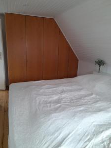 1 dormitorio con 1 cama blanca grande y cabecero de madera en TannenQuartier - Ihr Ferienhäuschen, en Groß Grönau