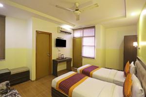 a hotel room with two beds and a tv at Hotel Aeroporto in New Delhi