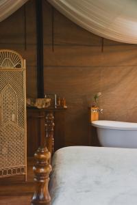 Silk Pavilions Glamping في Mount Burrell: غرفة نوم مع سرير وحوض استحمام ومغسلة