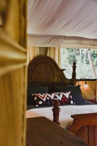 Silk Pavilions Glamping في Mount Burrell: غرفة نوم مع سرير المظلة مع الوسائد