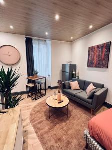 un soggiorno con divano e tavolo di Jadore - Appartements meublés Mulhouse Ville a Mulhouse